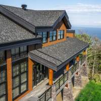 Chalet Ilaali dans Charlevoix avec terrasse couverte et galerie autour de la maison.